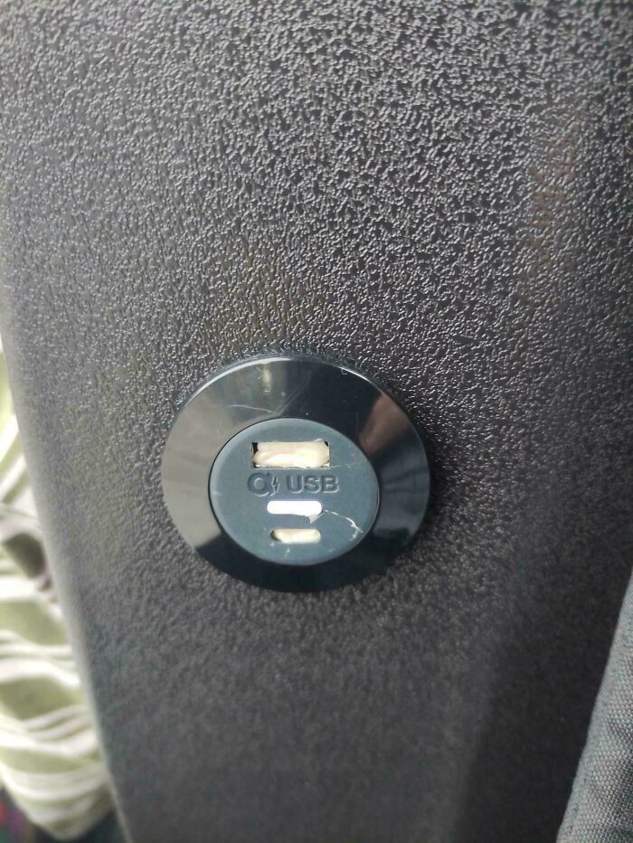 A dirty, broken USB port on a textured surface, indicating little hope for humanity in maintaining public amenities.
