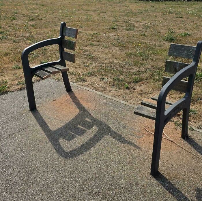 Two park benches facing away from each other, representing little hope for humanity in connection.