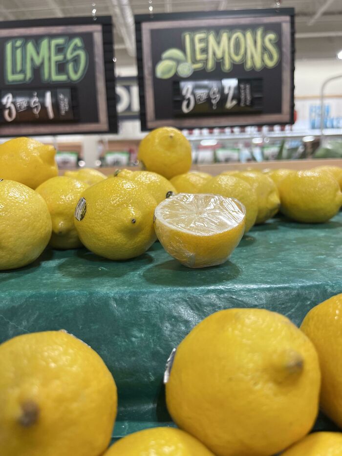 A single lemon cut in half and saran-wrapped on a produce stand, showing little hope for humanity.
