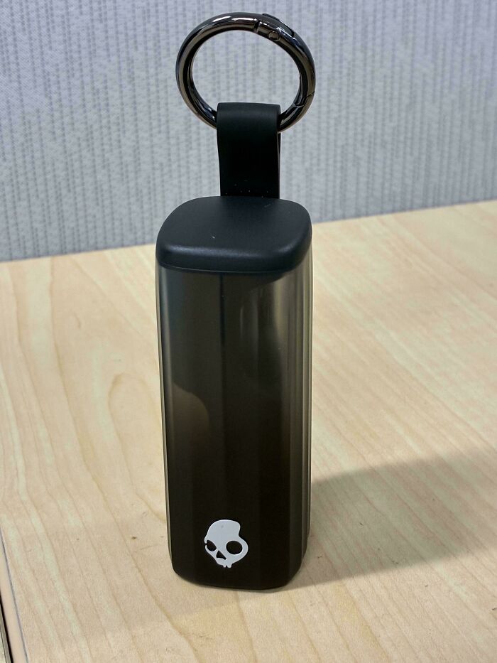 A black Skullcandy keychain on a wooden desk, representing little hope for humanity with a trivial object.