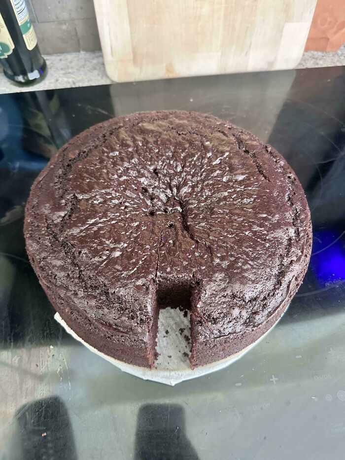 A chocolate cake with a large, square piece cut out, showing little hope for humanity in sharing etiquette.