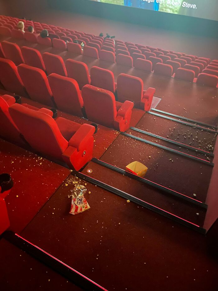 A messy movie theater floor covered in popcorn, highlighting a lack of respect and little hope for humanity's cleanliness.