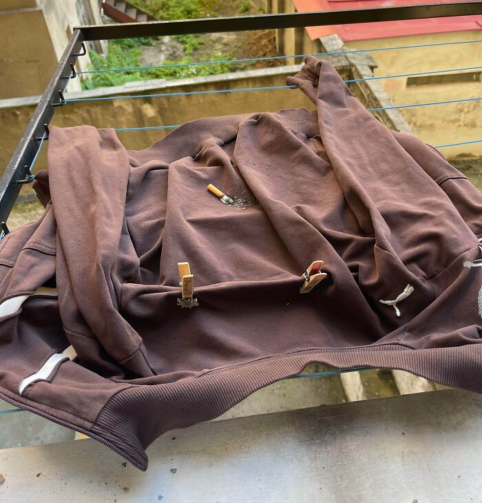A brown hoodie with a lit cigarette resting on it, illustrating a lack of hope for humanity.