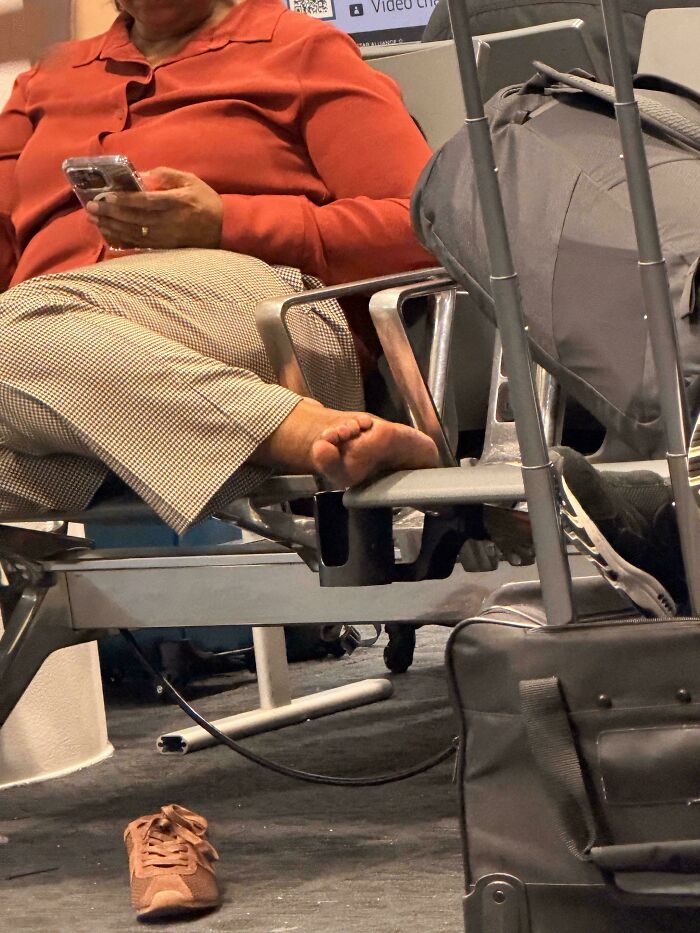 A person with bare feet propped on an airport chair, showing a lack of hope for humanity.
