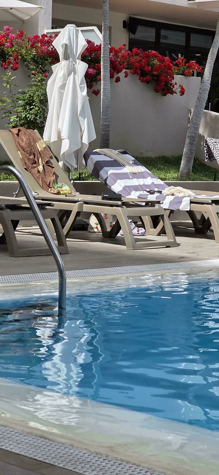 Sun loungers by a pool, showing little hope for humanity with abandoned items.