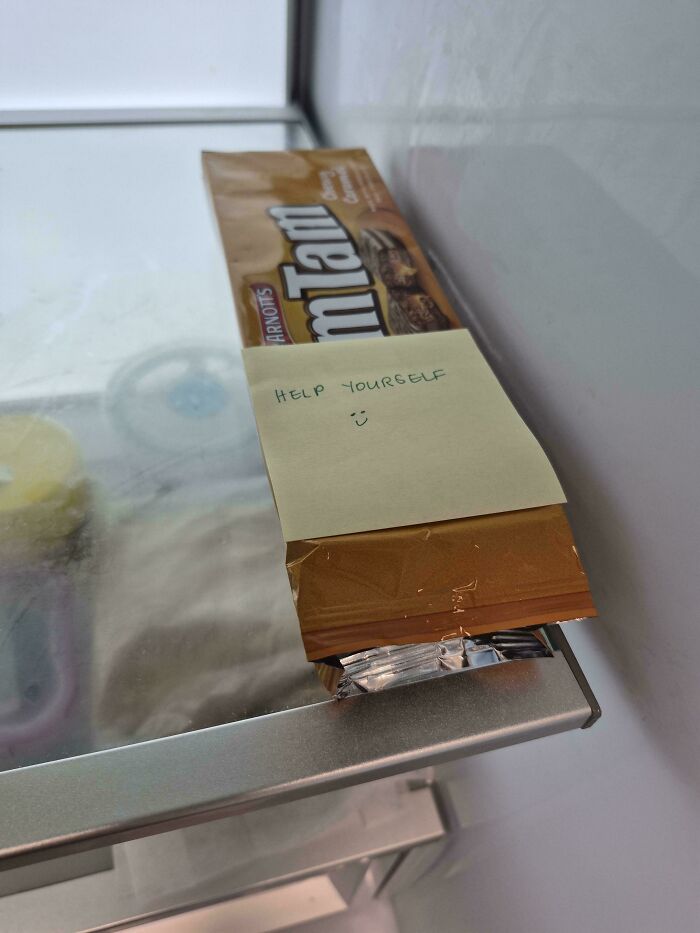 A package of Tim Tam biscuits in a refrigerator with a note saying Help Yourself, showcasing a glimmer of hope for humanity.