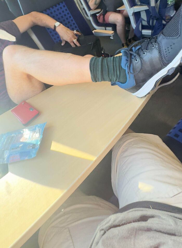 A person with their leg on a train table, showing little hope for humanity.