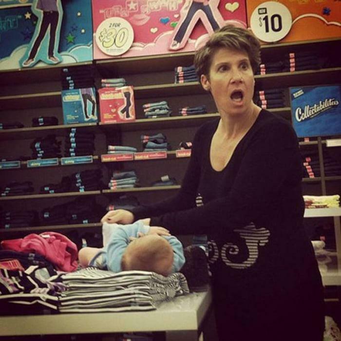 A woman with a surprised expression changing a baby's diaper on a store counter, illustrating little hope for humanity.