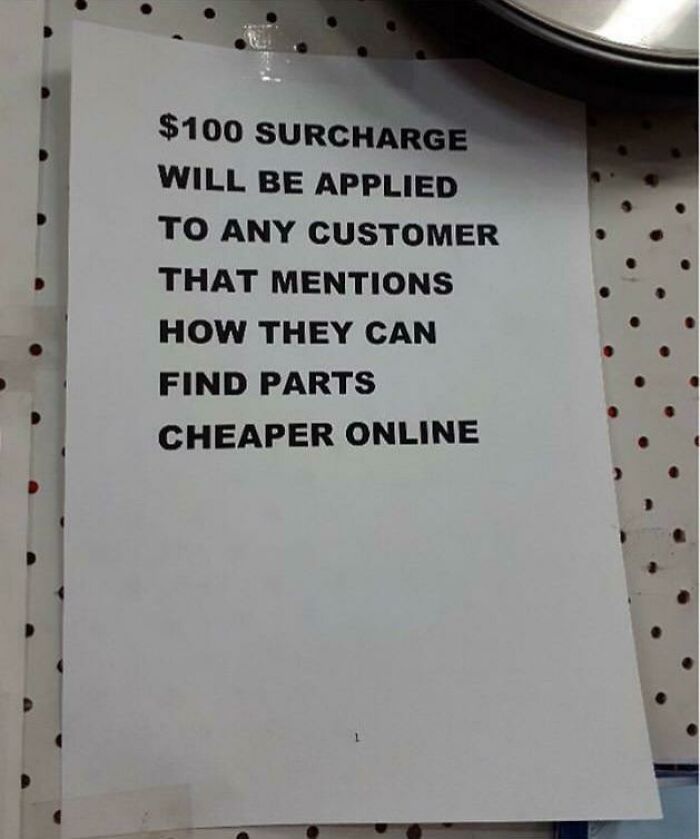A sign warning customers of a $100 surcharge for mentioning cheaper online parts, highlighting reasons for little hope for humanity.