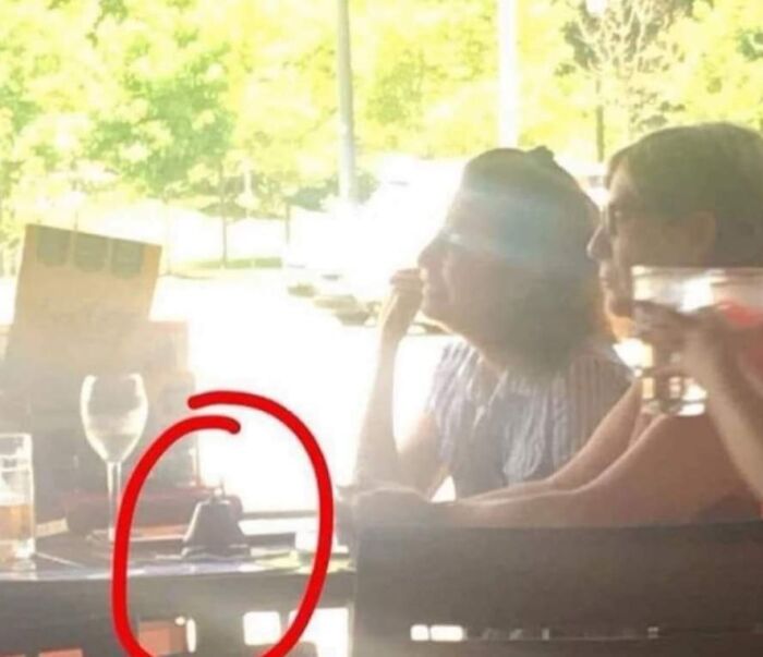 Two people at a sunny outdoor table, with a red circle highlighting a small object, symbolizing little hope for humanity.