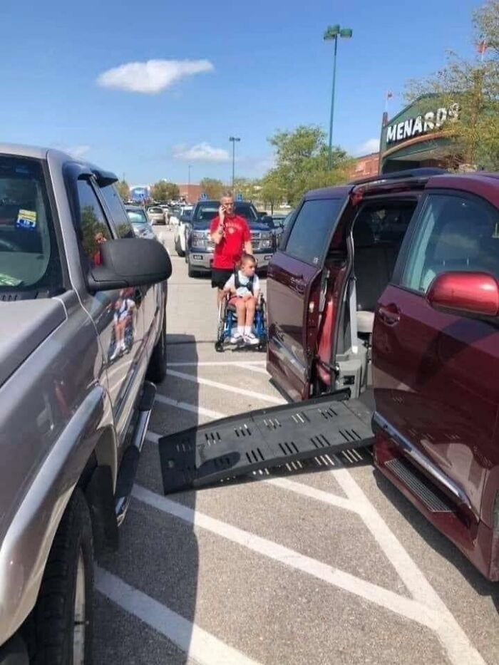 A man talking on phone, parking partially in a handicap spot, with a kid in a wheelchair, illustrating little hope for humanity.
