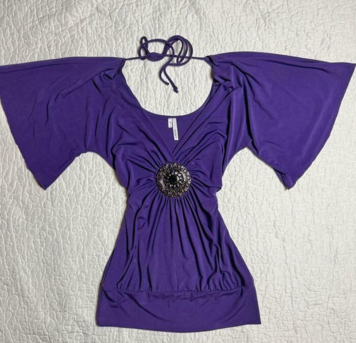 A vibrant purple women's top with wide sleeves and a decorative brooch, a fashion item lost hope to find.