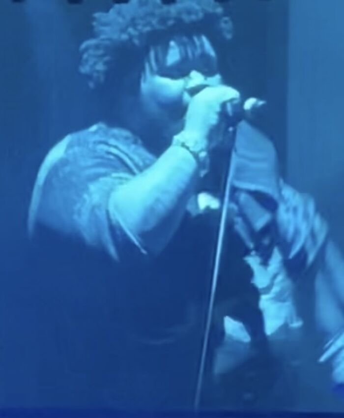 Rod Wave performing live on stage, capturing a highlight from his career, with a vibrant blue light.