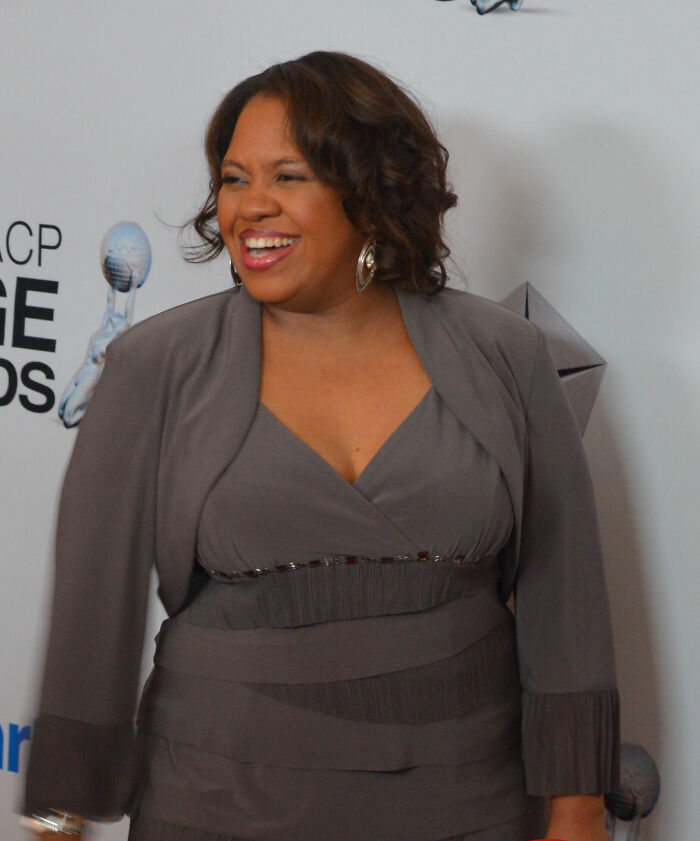 Chandra Wilson smiling and wearing a grey dress, attending an event, highlighting her career.