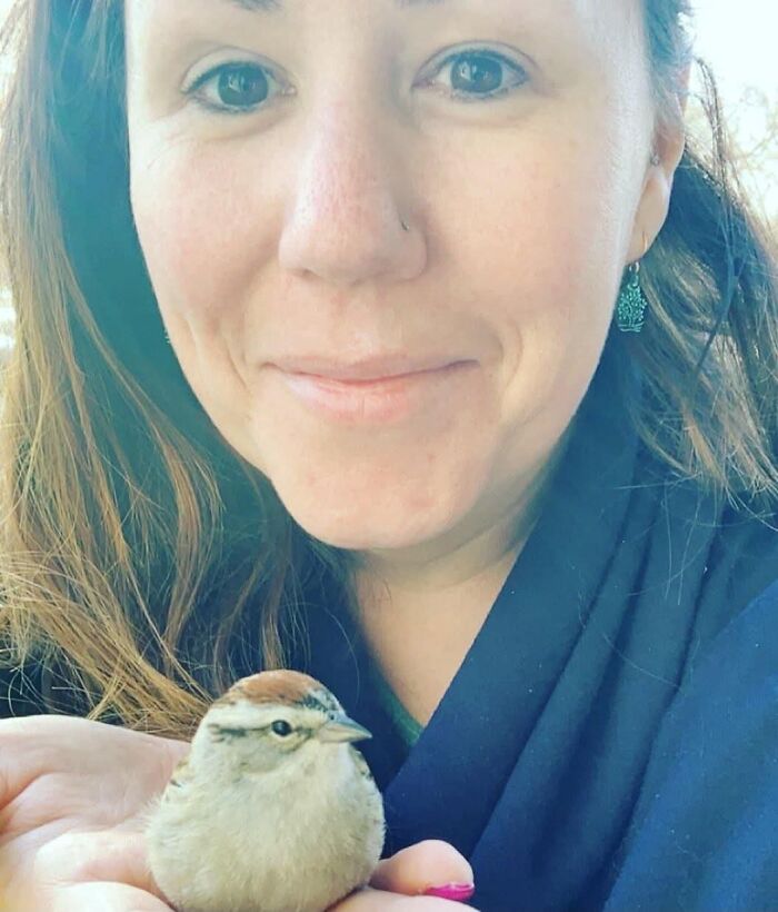 A woman smiling, holding a small bird in her hands, a sign from the universe for hope.
