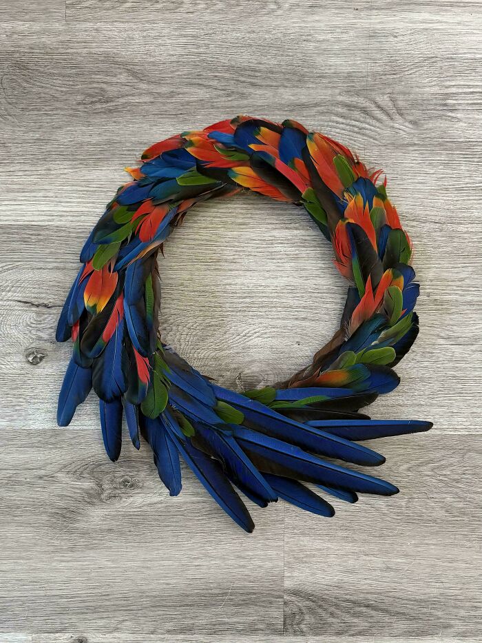 An amazing craft: a vibrant feather wreath with colorful feathers arranged on a wooden background.