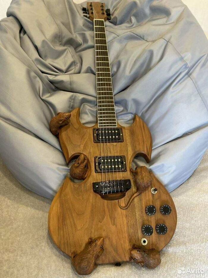 A wooden guitar with carved rats crawling on its body, an awful idea executed with disturbing levels of skill.