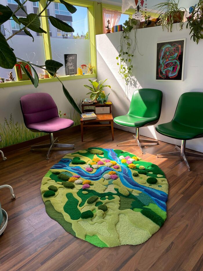 Vibrant rug depicting a lush landscape with a river and flowers, a stunning piece of amazing crafts in a room.