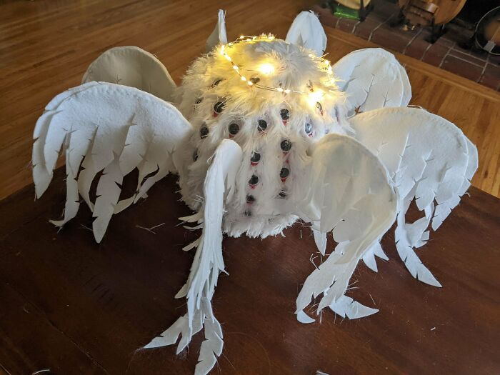 Amazing crafts: a large, fluffy white spider-like creation with many eyes and string lights for decoration.