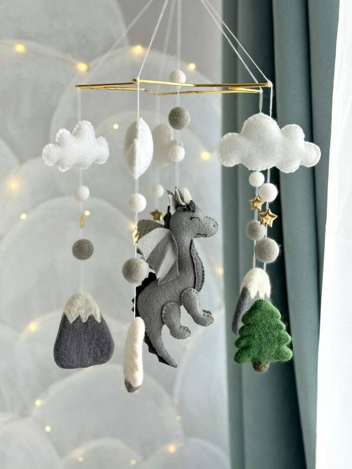 A baby mobile with felt crafts of a dragon, clouds, mountains, and trees, showcasing amazing crafts.