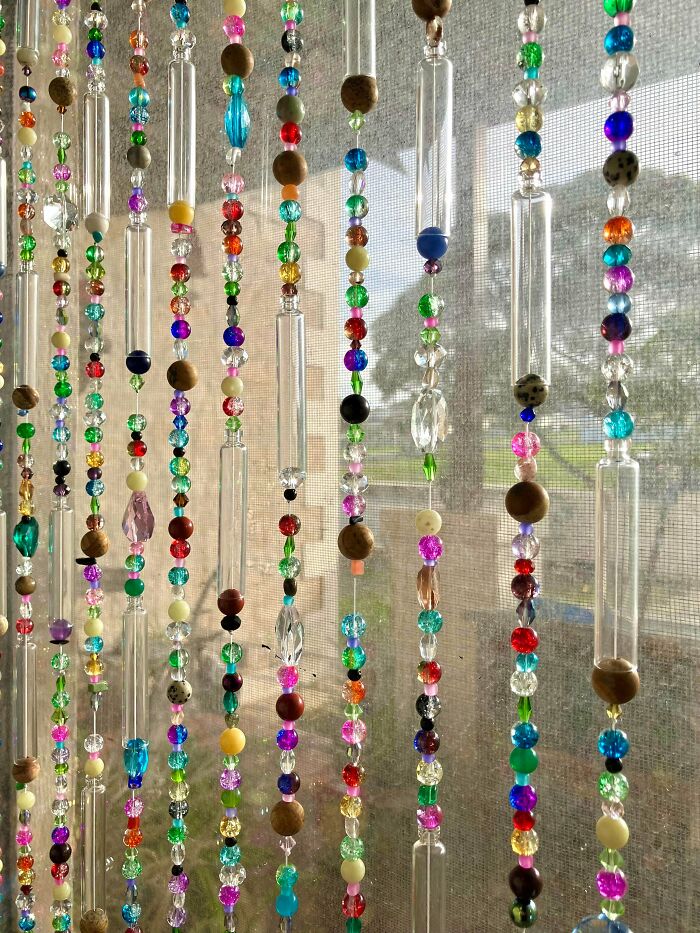 Colorful beaded curtains shimmering in the sunlight, featuring various beads and glass tubes, beautiful amazing crafts.