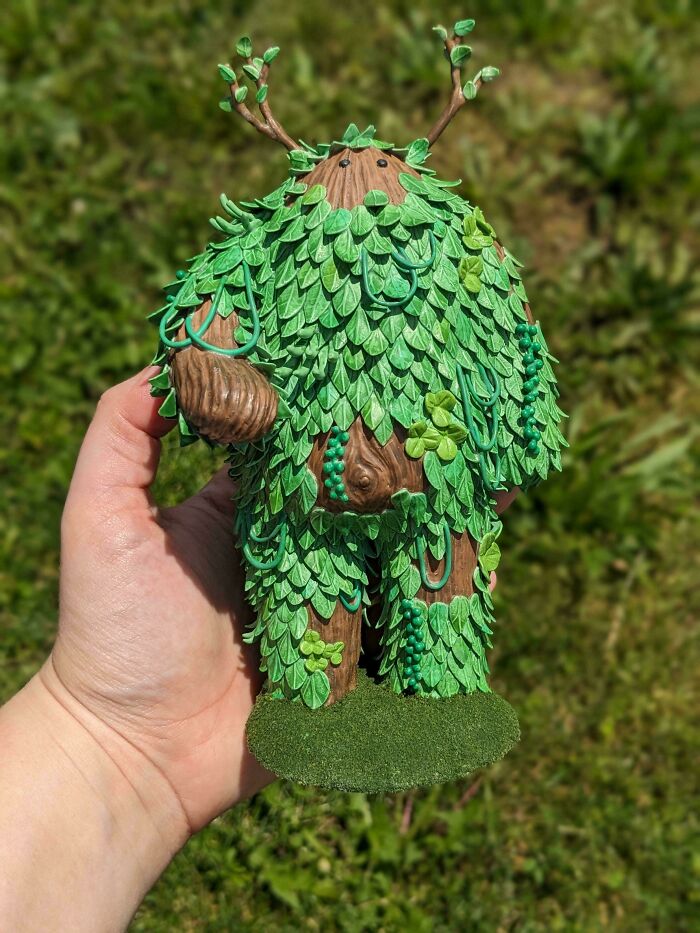 A handmade figurine of a creature covered in green leaves and branches, an amazing craft.