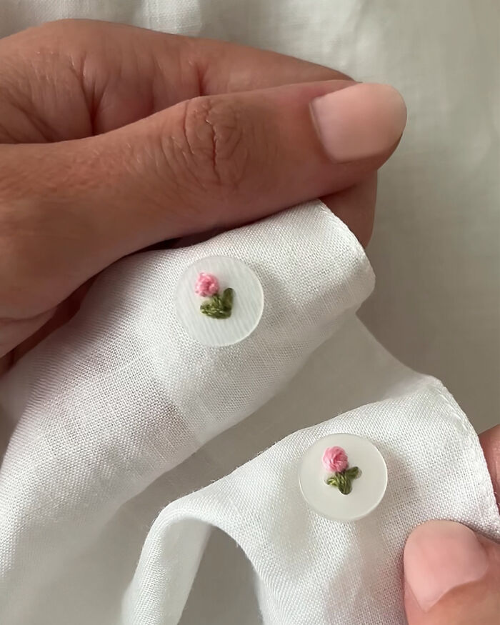 Amazing crafts with tiny embroidered pink roses on white buttons, held by fingers.
