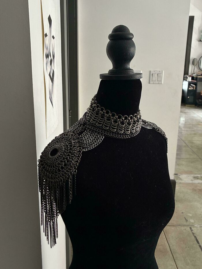 Amazing crafts: a detailed chainmail shoulder piece displayed on a black mannequin, showcasing intricate craftsmanship.