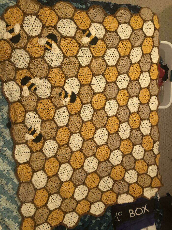 A cozy, crocheted blanket with a honeycomb and bee pattern, an example of amazing crafts.