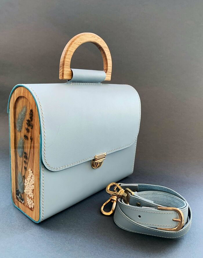 Amazing crafts: Stylish handbag made of light blue leather and wood with dried flowers, showcasing people's ability to go above and beyond.