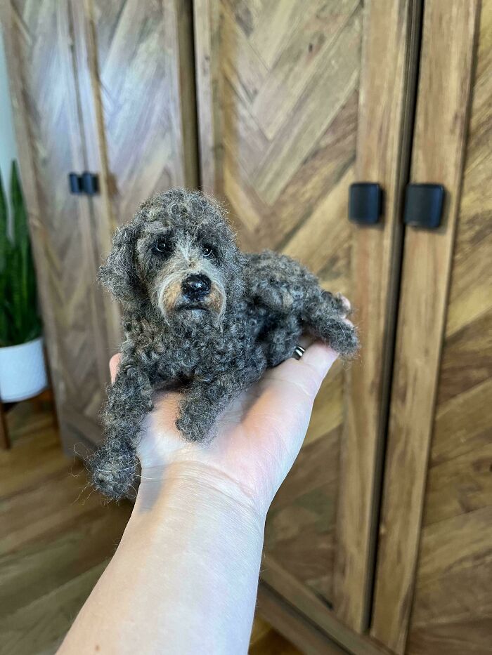 A tiny, realistic felted dog held in a person's hand, showcasing amazing crafts.