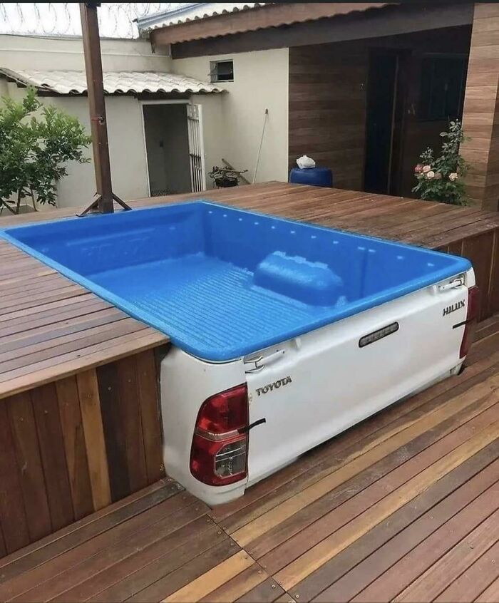 A truck bed repurposed as a small pool on a wooden deck, an awful idea executed with skill.