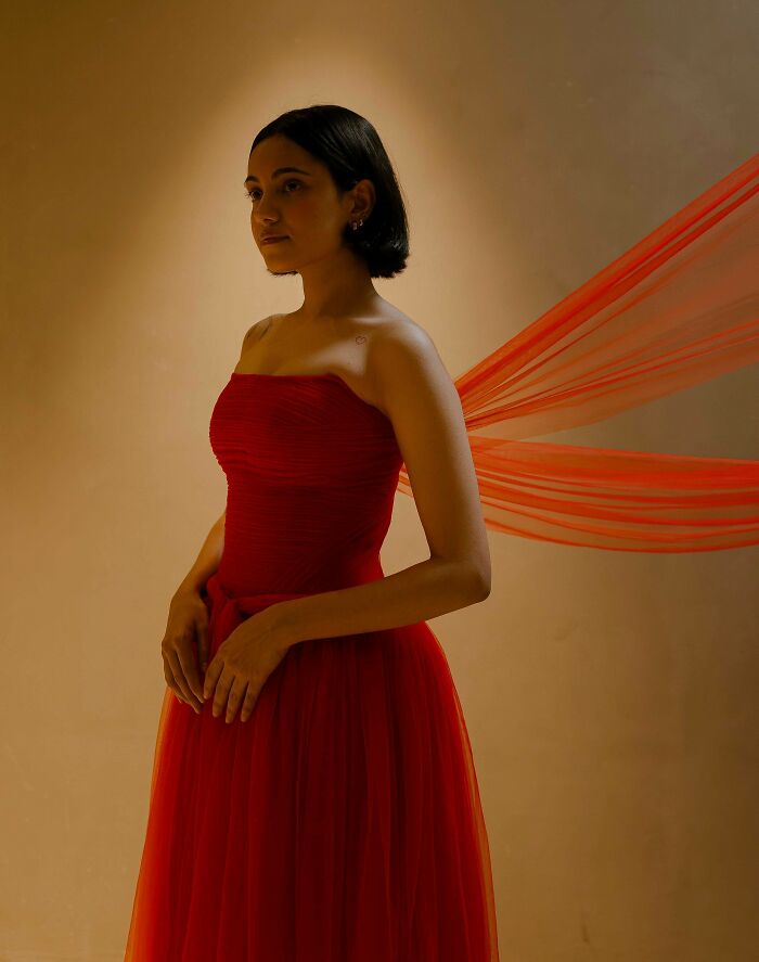 A woman in a flowing red gown, embodying above and beyond fashion crafts.