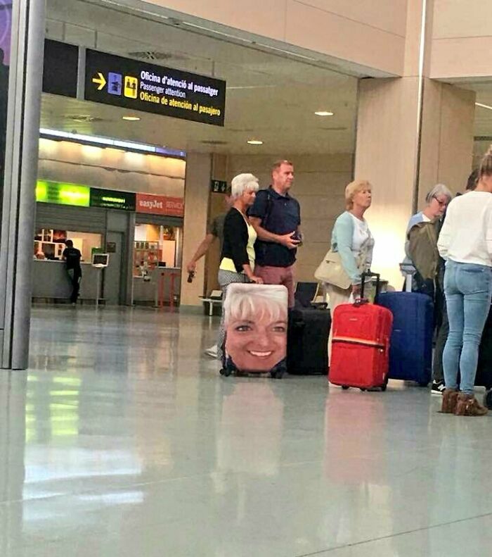 A suitcase with a woman's face printed on it at an airport, an awful idea executed with skill.