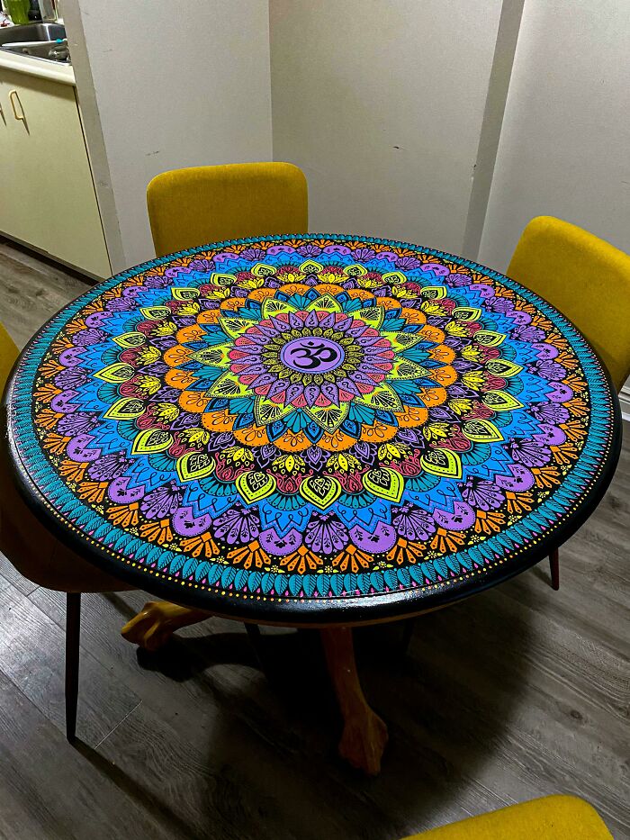 A vibrant, intricately painted mandala table, showcasing amazing crafts and people going above and beyond.