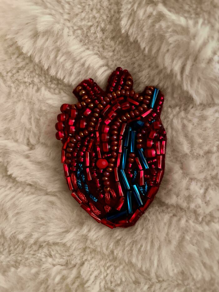 Amazing crafts: Intricate beaded heart pin with red and blue beads on a fluffy white surface, showcasing creative talent.