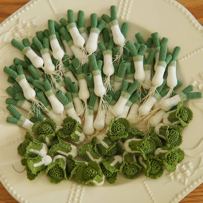 Amazing crafts: A pile of delicately crocheted scallions and cabbage heads on a white decorative plate, showcasing amazing crafts.