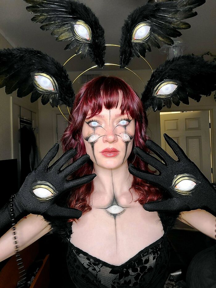 An amazing craft of a person with elaborate makeup and costume featuring multiple eyes and black feathered wings.