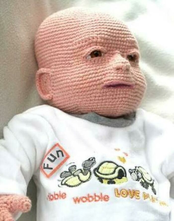 A crocheted baby doll with a realistic, slightly unsettling face, an awful idea with skill.
