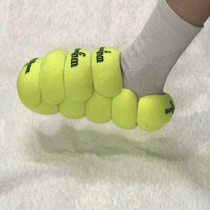 A foot in a white sock wearing a sandal made of tennis balls, an awful idea with disturbing skill.