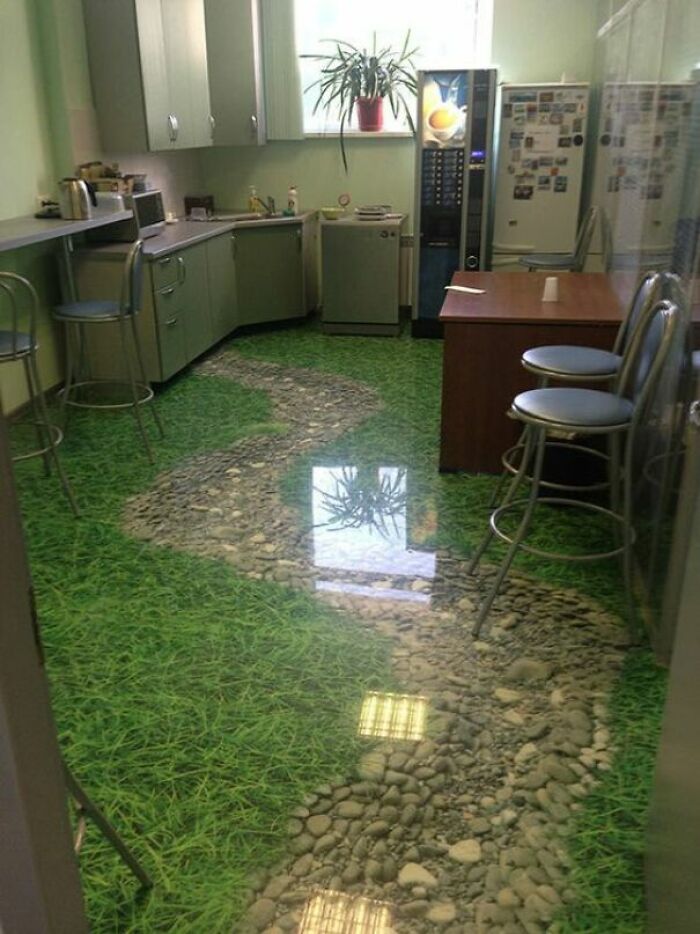 A kitchen with a 3D floor design resembling a grassy path with stones, an awful idea executed with skill.
