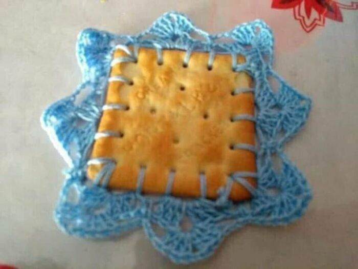 Awful idea: a disturbing cracker sewn into a crocheted doily, executed with skill.