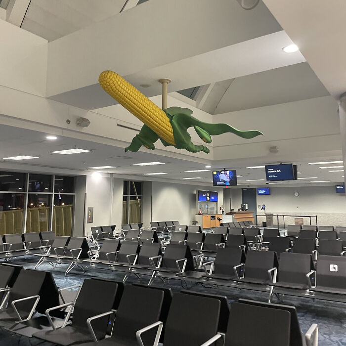 Giant corn cob hanging from the ceiling in an airport, an awful idea with disturbing levels of skill.