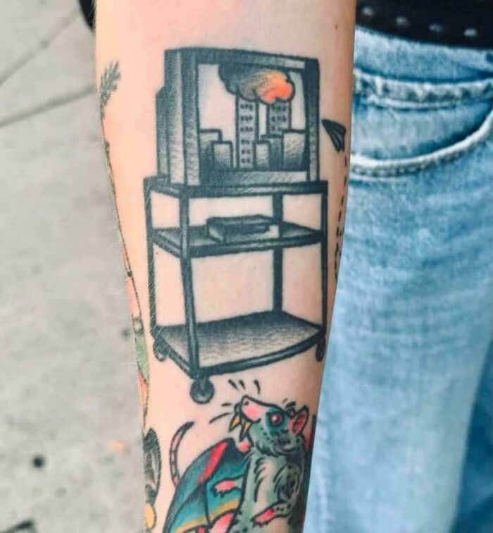 A tattoo of a TV with disturbing levels of skill showing a city and smoke, an awful idea.