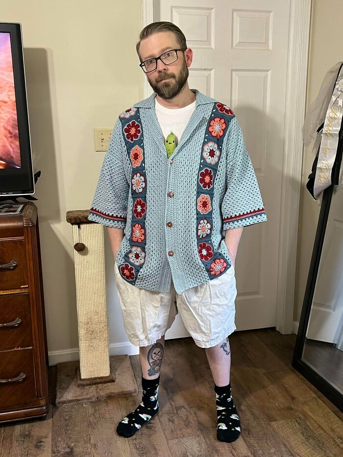 Man wearing a blue crochet cardigan with flower pattern indoors