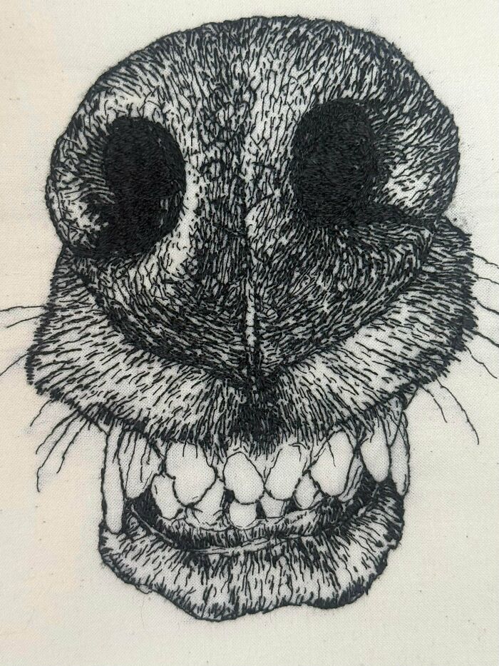 A detailed embroidery project of a dog's nose and teeth using black and white thread