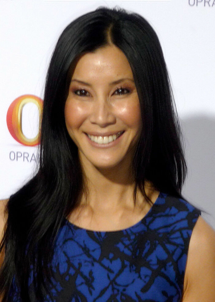Lisa Ling smiling in a blue and black patterned top, showcasing her bio and career highlights.