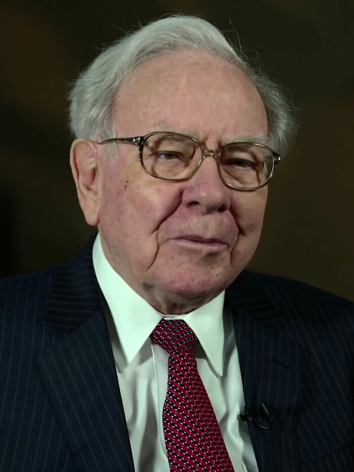 Close-up of Warren Buffett, in a pinstripe suit and red tie, highlighting his career.