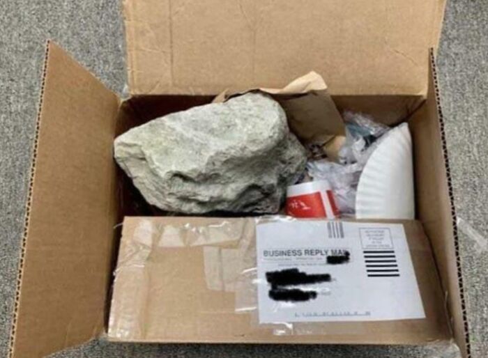 An open box filled with trash and a boulder with a business reply mail label, a perfect way someone got back at someone.