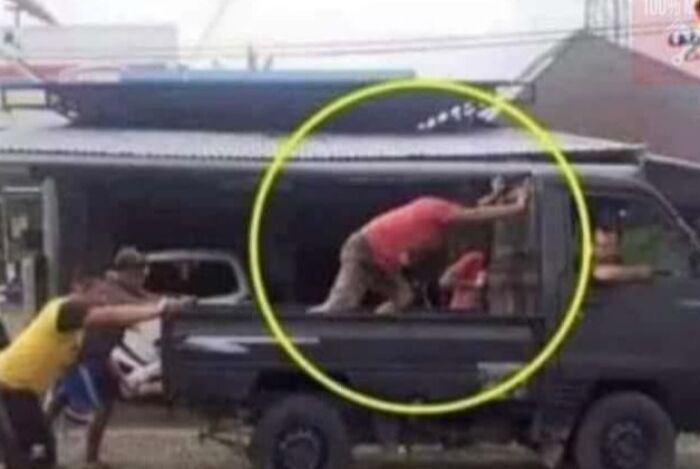 Several people pushing a truck while one person inside leans on the window, showcasing a dumb survival attempt.
